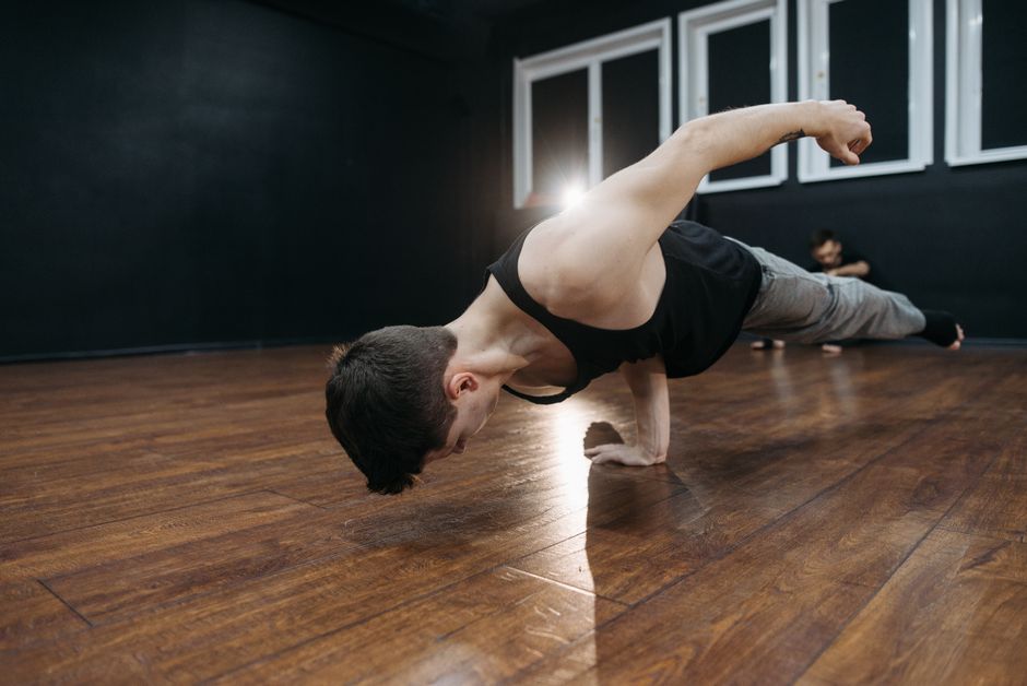 A breakdancer showcasing strength and flexibility in a dance studio.