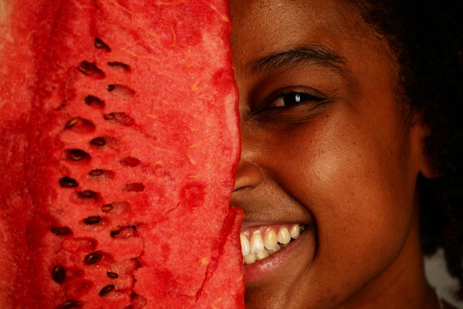 A cheerful person holding a watermelon slice close to the face, showcasing a joyful expression.