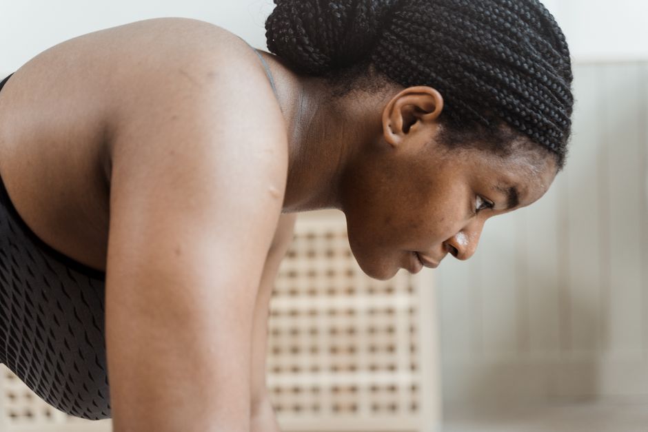 A determined woman in a black tank top doing an indoor workout, showcasing strength and fitness.