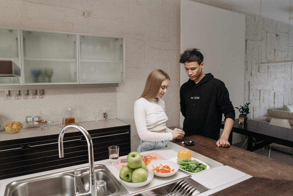 A man and woman checking a glucometer reading in a modern kitchen setting.