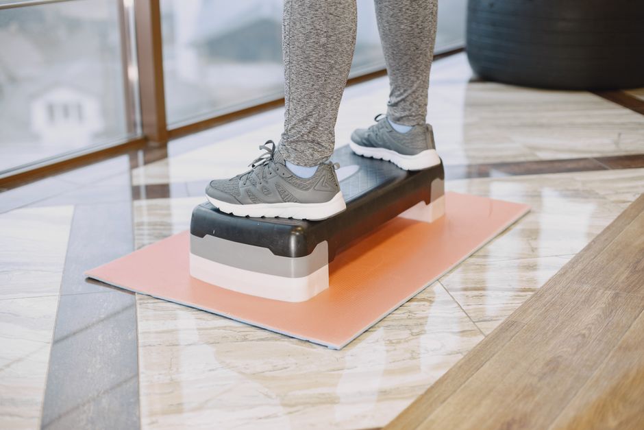 A person exercising indoors using a step platform for a workout routine.