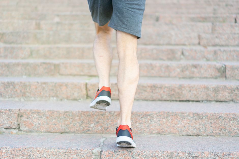 A person in athletic shoes climbing stone steps, showcasing determination and fitness.