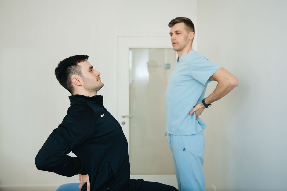 A physiotherapist instructs a patient on back exercises in a clinic setting.