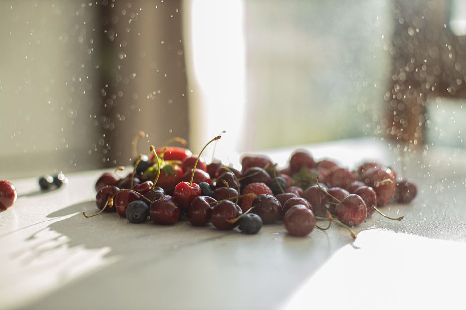 A refreshing assortment of cherries and blueberries with water droplets on a sunny table.