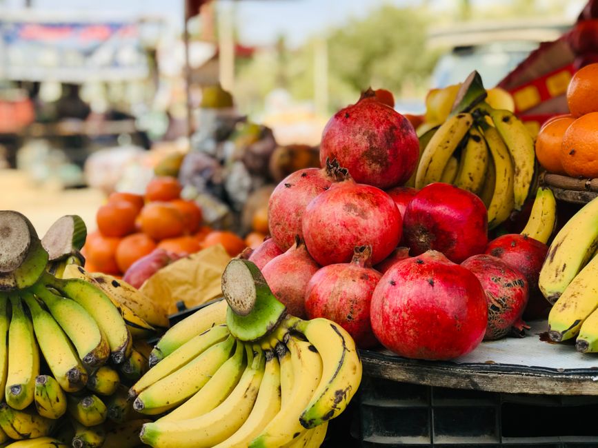 A vibrant display of bananas, pomegranates, and various fruits at an outdoor market. Fresh and healthy selection.