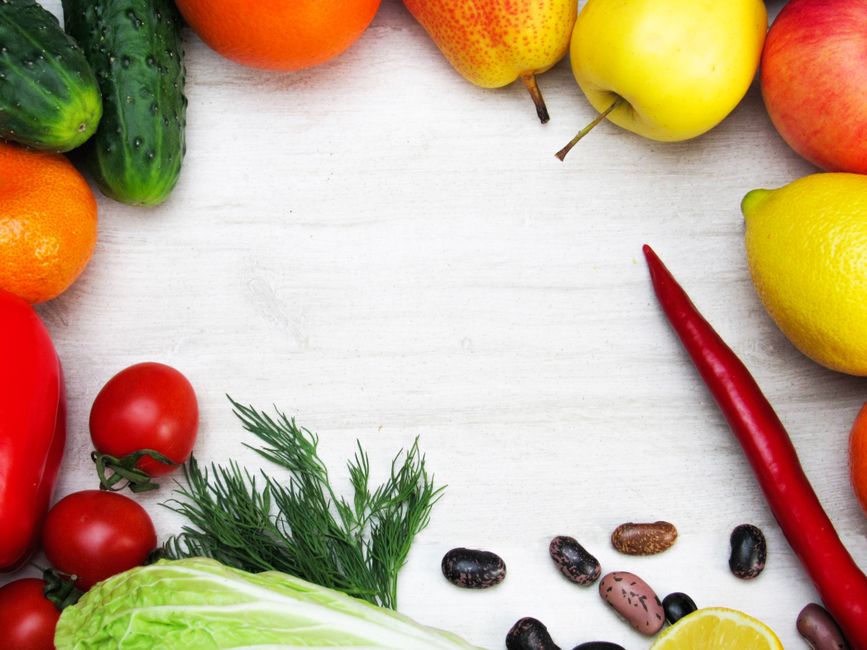 A vibrant flat lay of fresh fruits and vegetables with ample copy space on a white background.