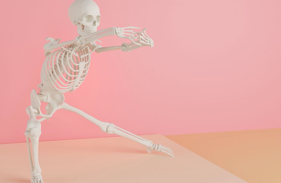 A white skeleton model striking a dynamic pose on a pink and peach background.