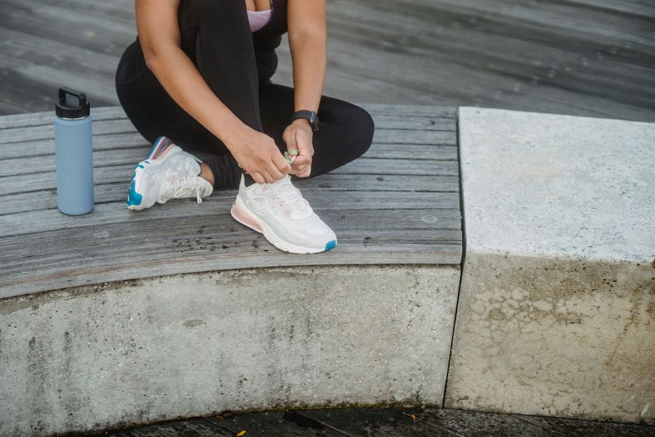 Active woman ties her sneakers on a concrete bench, ready for workout.