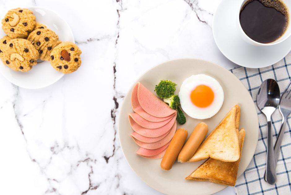 An appetizing breakfast spread featuring eggs, sausages, toast, and coffee on a marble surface.