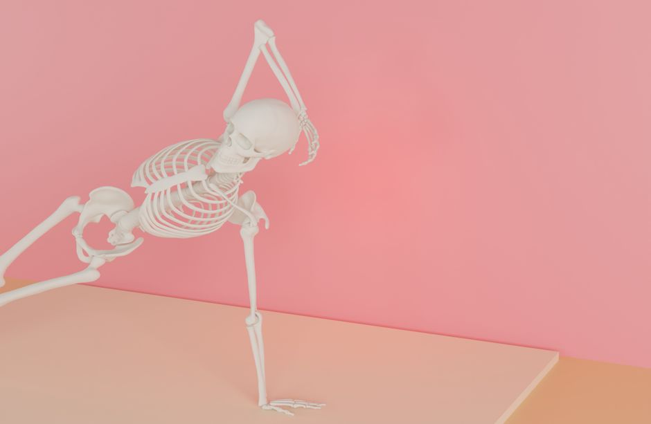 Artistic still life of a skeleton in a yoga pose against a pastel pink background.