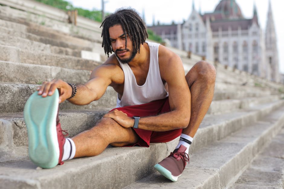 Athletic man stretching on city steps, embracing fitness and urban lifestyle.
