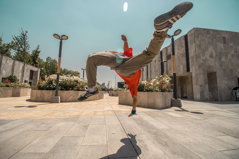 Captivating street dance midair flip by a dynamic performer in an urban setting.