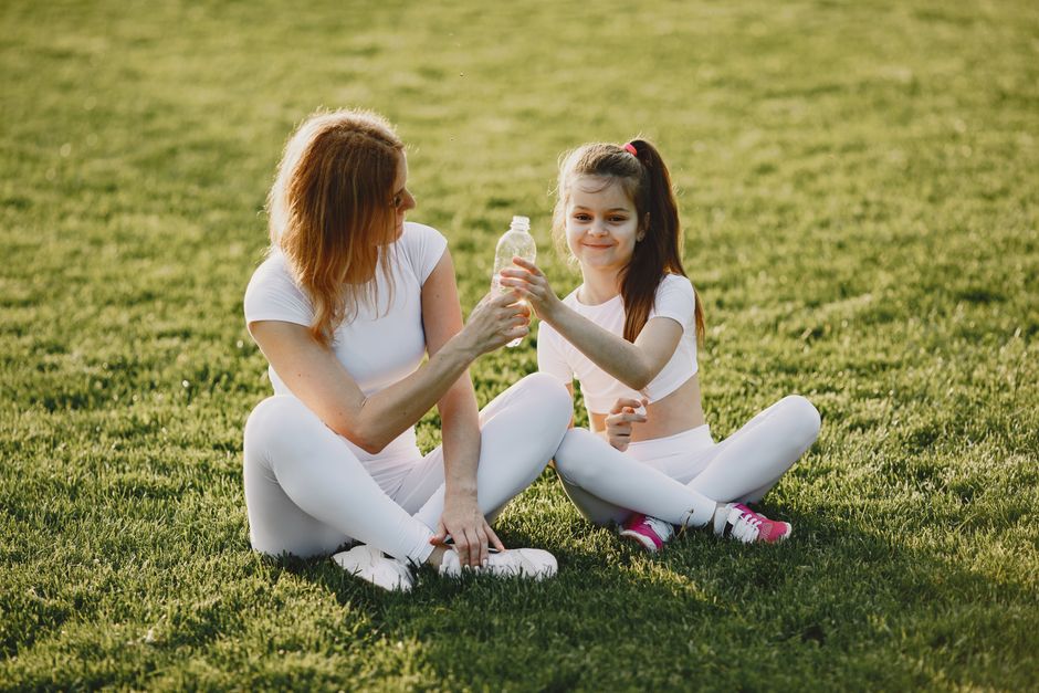 Caucasian mother and daughter in sportswear sharing a bonding moment outdoors.