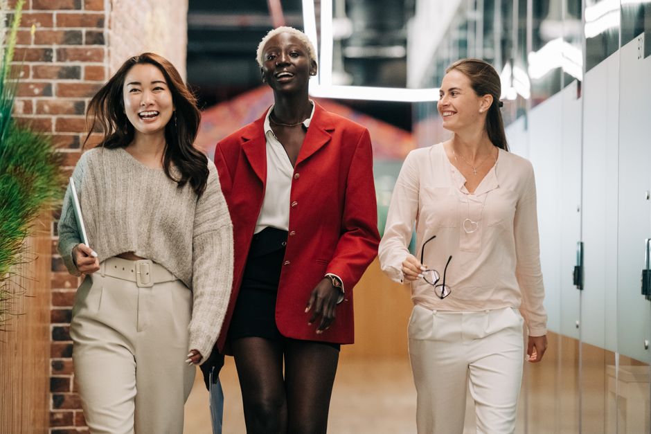 Cheerful diverse businesswomen in elegant clothes walking and smiling in contemporary office of business center