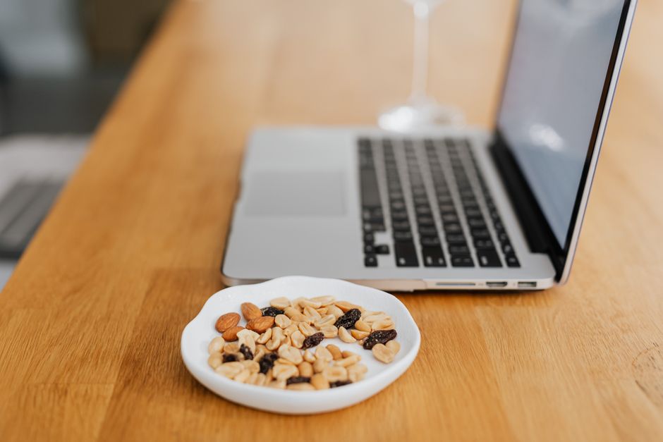 Close-up of a healthy snack beside a laptop on a wooden table, perfect for productive work breaks.