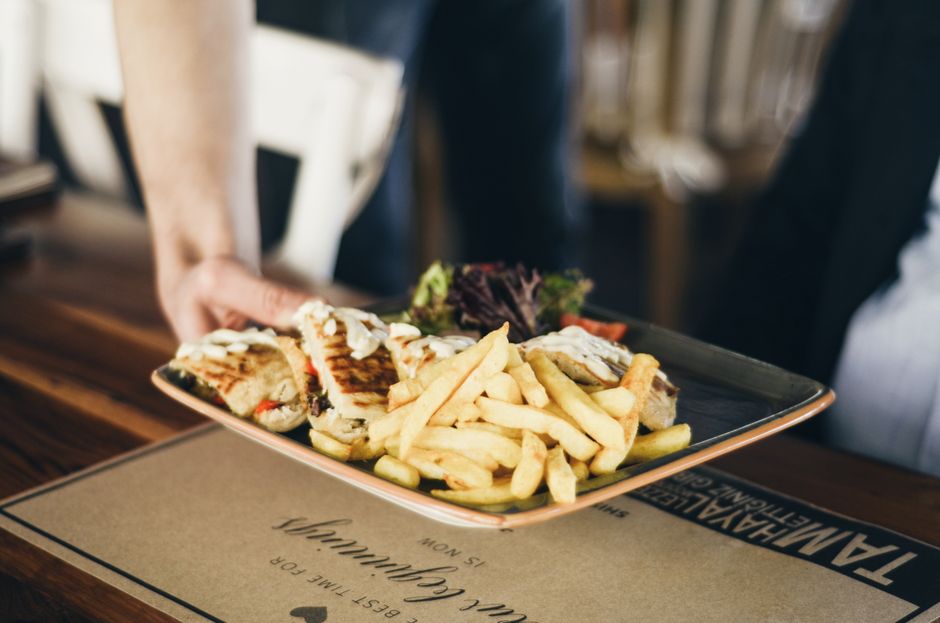 Close-up of a platter with French fries and sandwiches served indoors at a restaurant.
