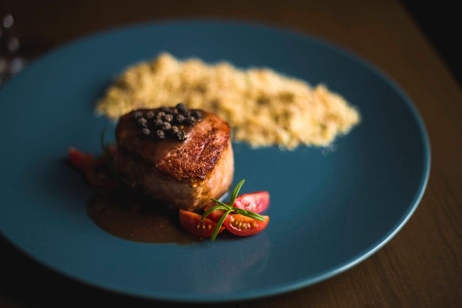 Close-up of gourmet beef steak with peppercorn sauce and cherry tomatoes.