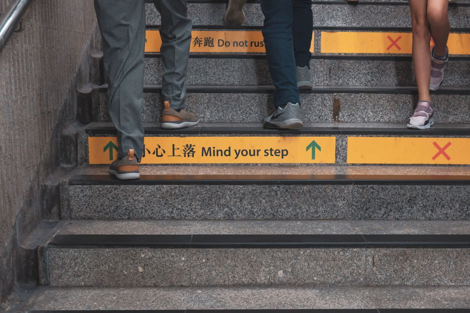 Close-up of people walking up stairs with safety signs in a subway station.