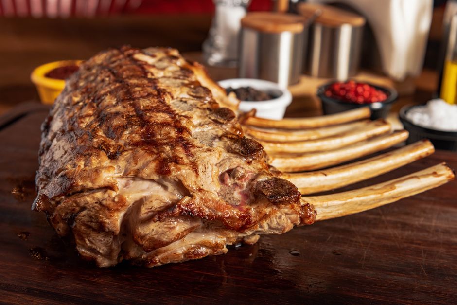 Close-up of seasoned grilled rack of lamb ribs on a rustic wooden board, perfect for gourmet dining.