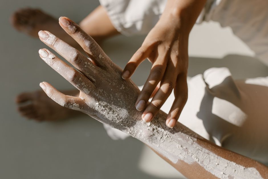 Close-up of two hands engaged in a clay treatment, capturing texture and artistic touch.