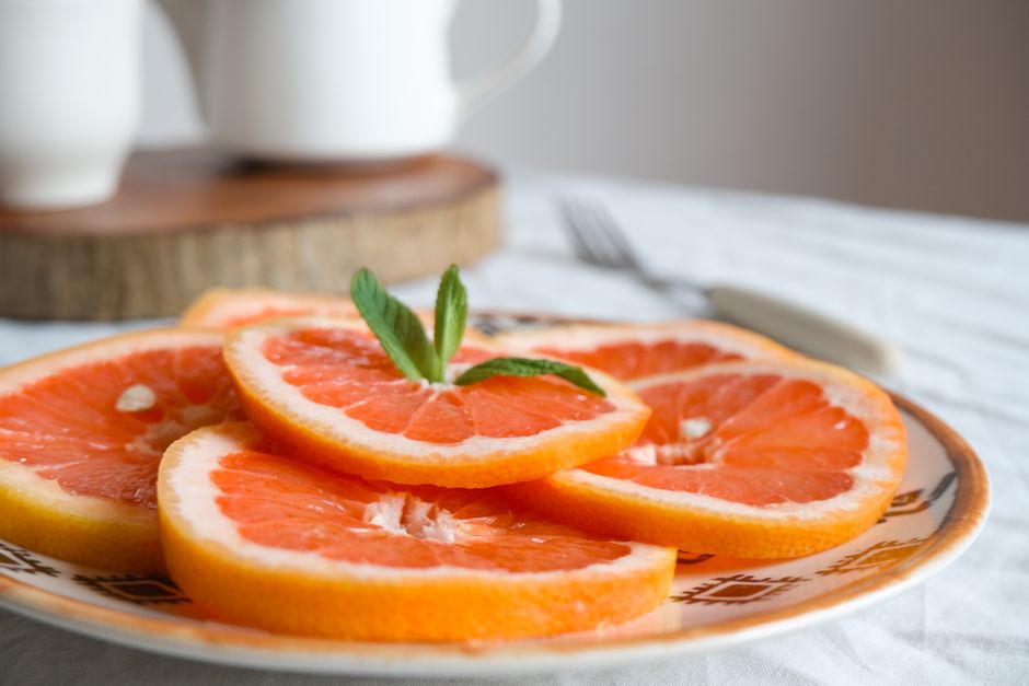 Crisp grapefruit slices on a plate with a fresh mint garnish, ready to enjoy.