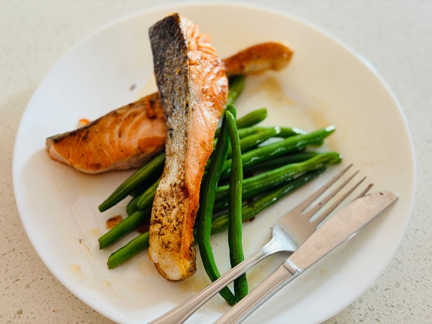 Delicious grilled salmon fillet served with fresh green beans on a white plate, perfect for a healthy meal.