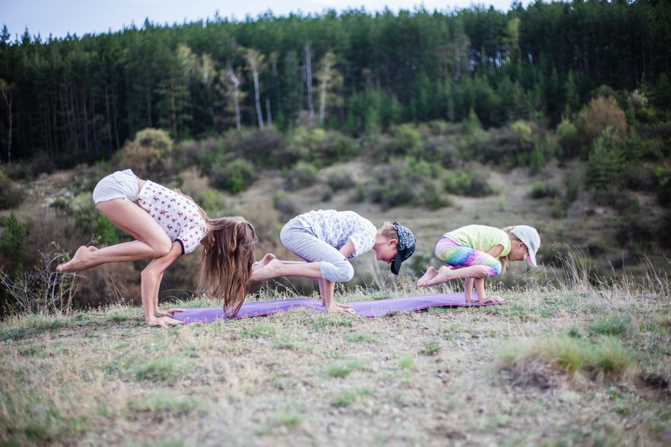 Family practicing yoga on a serene hillside, enjoying nature and wellness together.