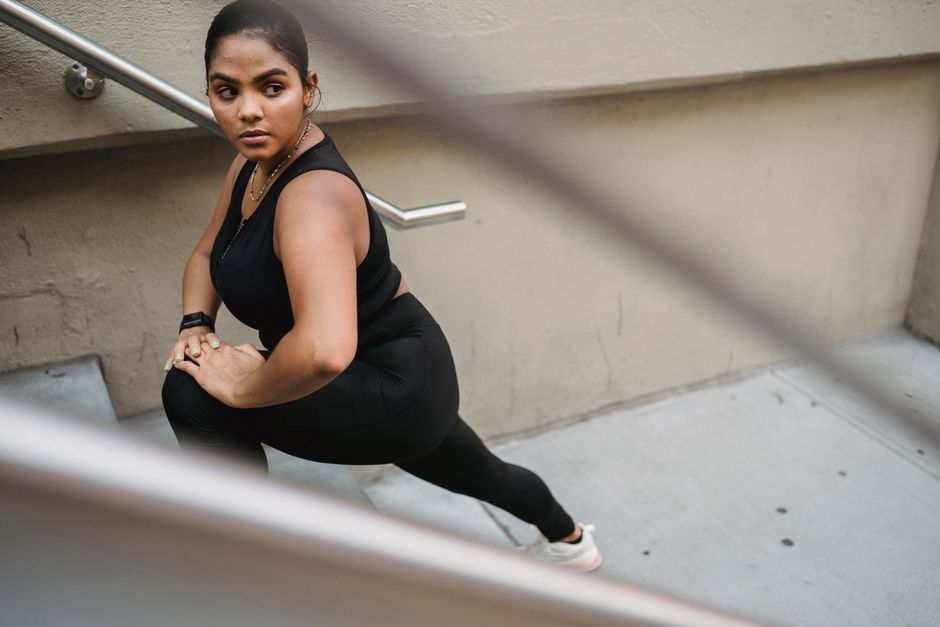 Fit woman stretching on outdoor stairs, wearing sports clothing. Health and fitness concept.