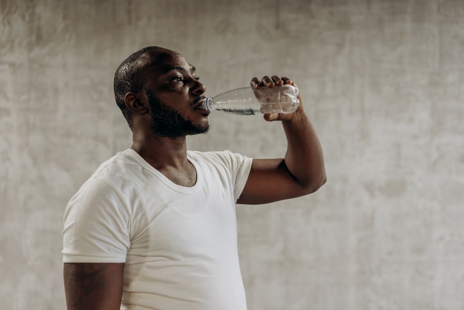 Healthy living concept: Man staying hydrated with water. Indoors, fitness focus.