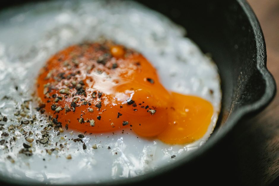 High angle of frying pan with delicious fried egg topped with dried herbs