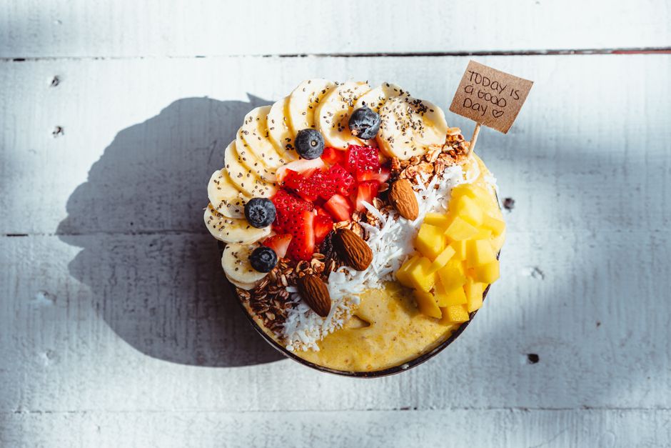 Indulge in this vibrant fruit smoothie bowl topped with banana, mango, and berries for a healthy treat.