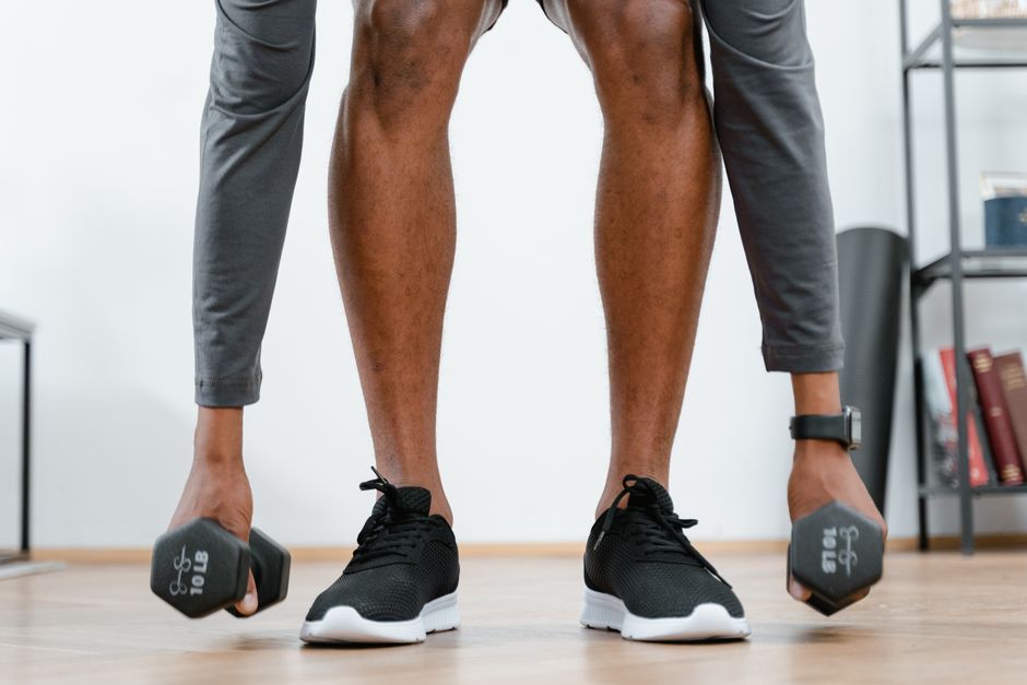 Person engaging in a home workout lifting dumbbells, promoting fitness and healthy living.