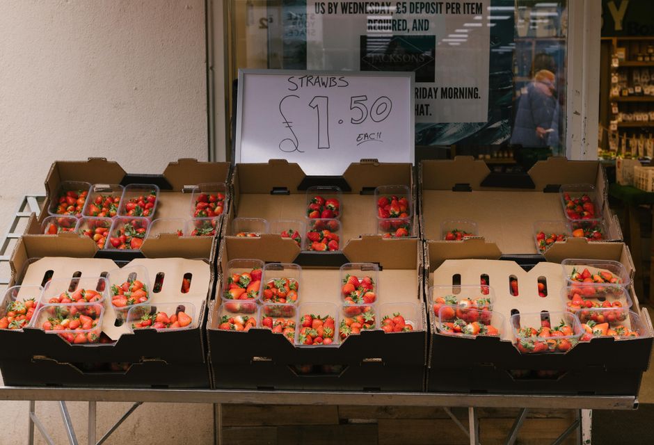 Plastic containers of strawberries for sale at a market stall, priced at £1.50 each.