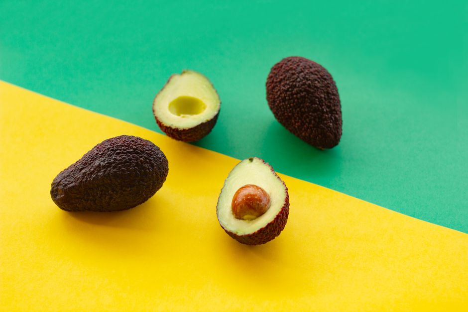 Ripe avocados displayed on vibrant green and yellow background, perfect for culinary themes.