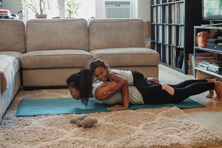 Side view of young Hispanic female athlete having fun with daughter while doing exercise