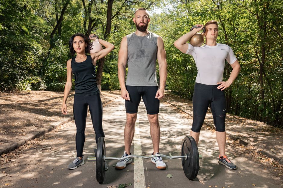 Three adults exercising outdoors with weights, promoting fitness and diversity.