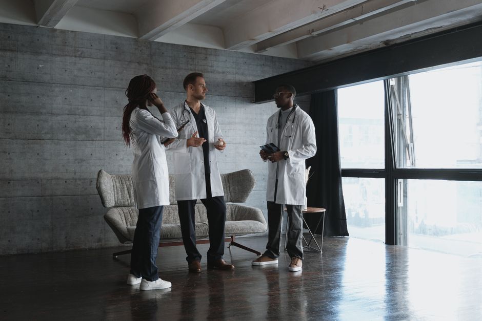 Three doctors in a modern office discussing medical matters in natural light.