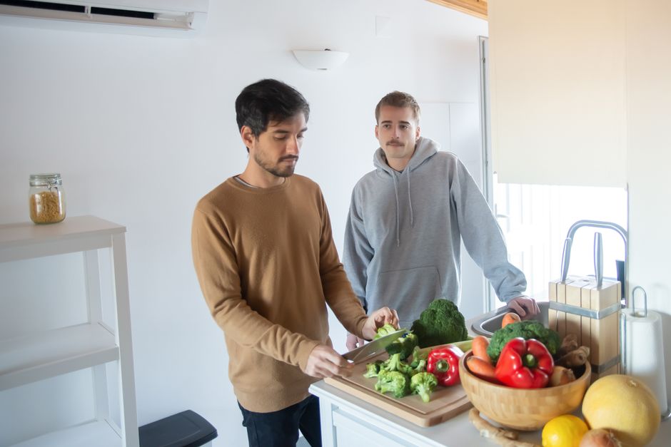 Two adults in a kitchen chopping vegetables, focusing on healthy meal preparation.