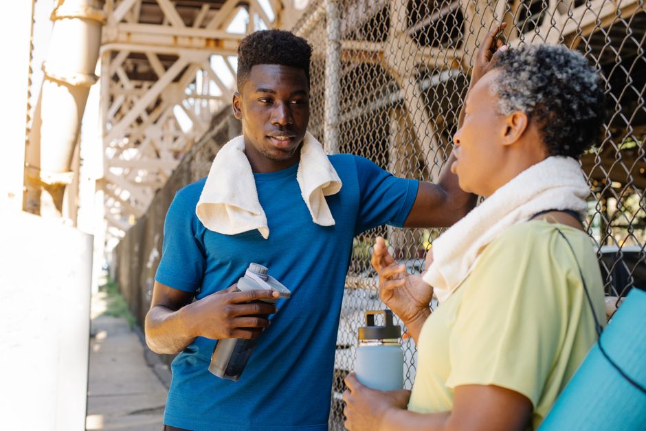 Two adults in sportswear resting outdoors, engaging in lively conversation and rehydration.