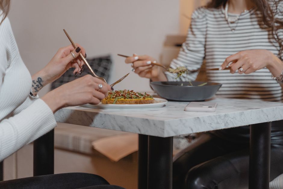 Two women sharing a healthy meal indoors, emphasizing friendship and togetherness.
