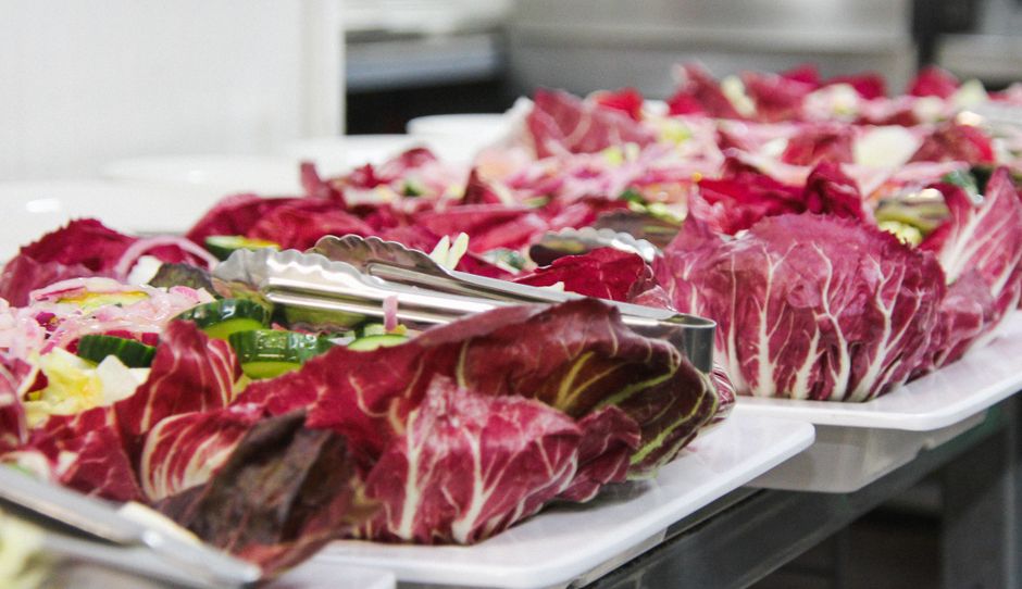 Vegetable platter with vibrant radicchio, cucumbers, and onions served with tongs.