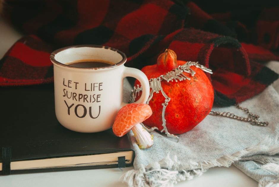 Warm autumn scene with a motivational mug, pomegranate, and blanket for cozy vibes.