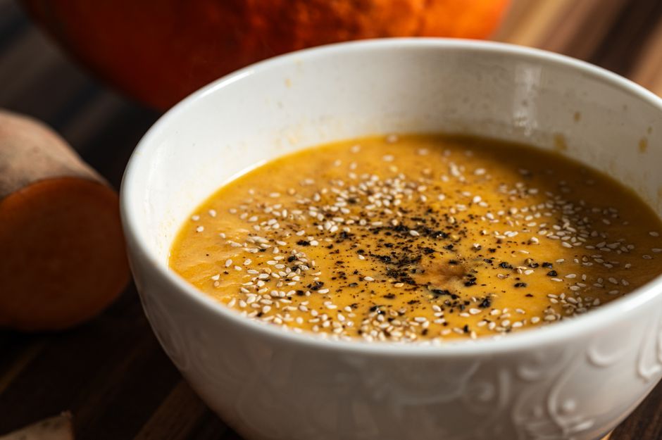 Warm pumpkin soup garnished with sesame seeds and pepper, perfect for a cozy meal.