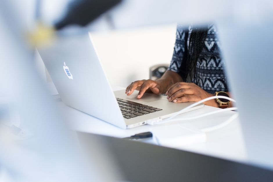 Woman typing on a laptop at a desk in a modern office setting, focused on work.