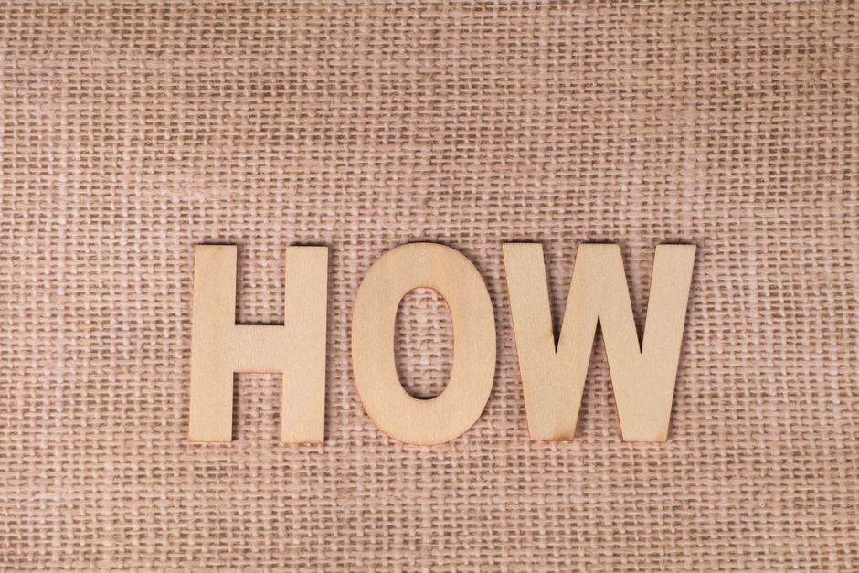 Word 'HOW' formed with wooden letters on textured burlap surface.