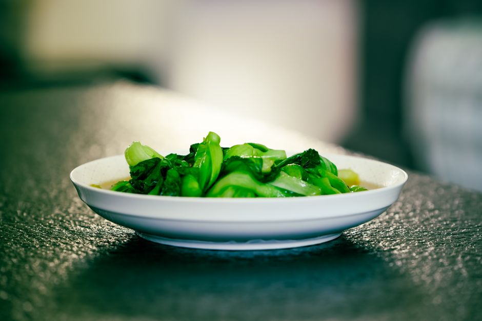 A bowl of vibrant green spinach leaves on a textured surface, perfect for healthy food concepts.