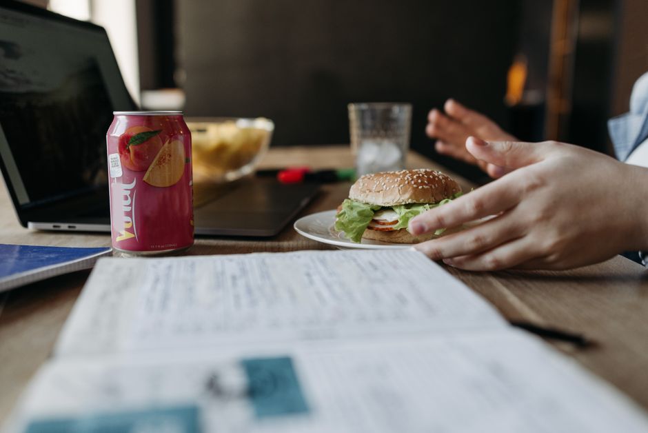 A casual office lunch with a burger and drink at a desk, showcasing work-life balance.