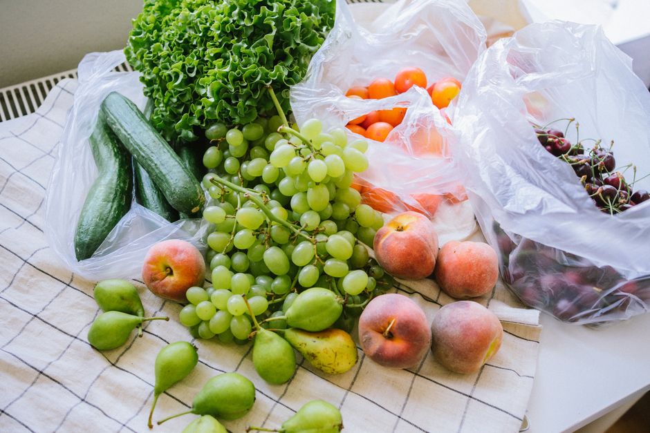 A colorful display of fresh fruits and vegetables on a table with plastic bags.
