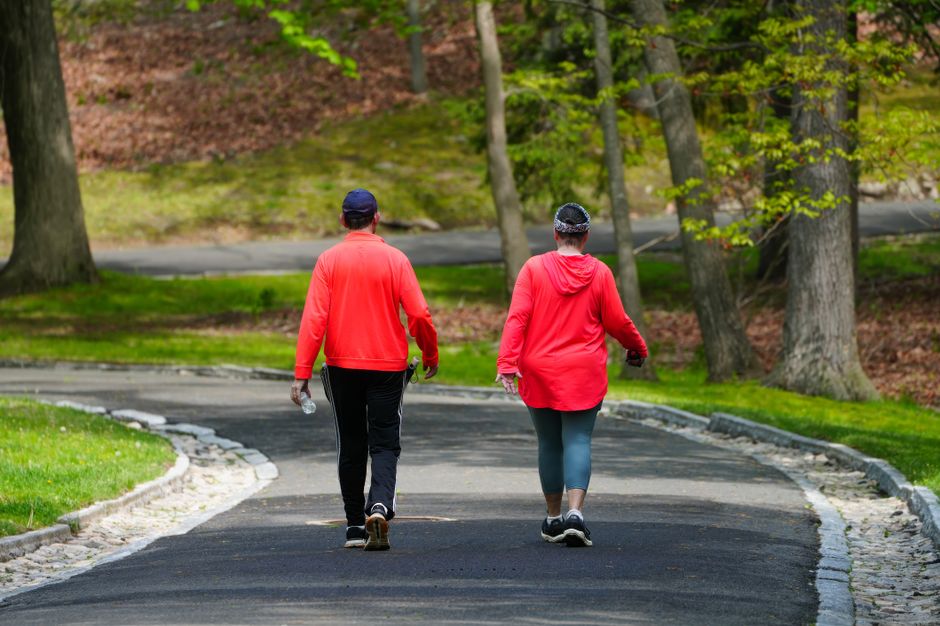 A couple enjoys a walk through a lush green park on a bright spring day.
