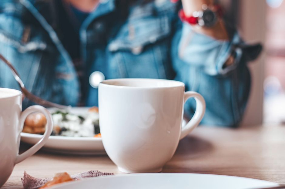 A cozy coffee break featuring white ceramic mugs on a wooden table with a blurred background.